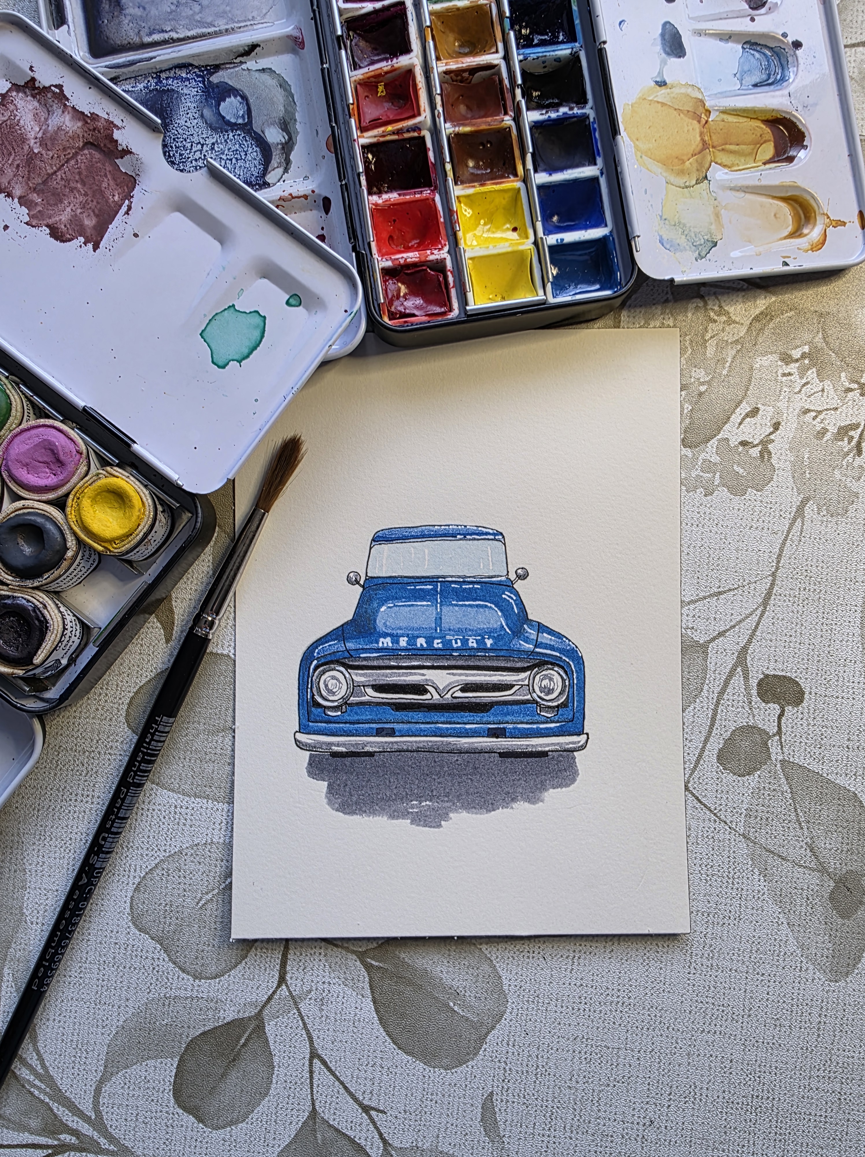 The image depicts a watercolor painting of the front-end design of a vintage 1950's Mercury car in metallic blue. The cent...